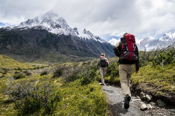 徒步旅行者穿越秋季金色的森林小径，背包上挂着登山杖